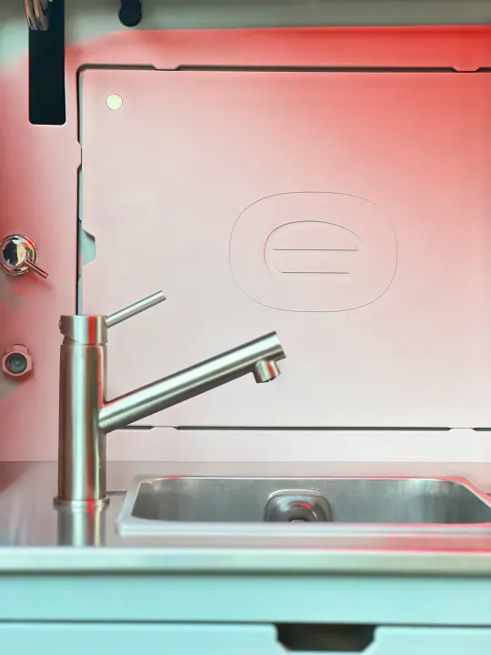 Compact kitchen setup in an RV rental, showcasing a stainless steel sink, sleek faucet, and modern paneling.. Escapod Escapod Trailer 2023