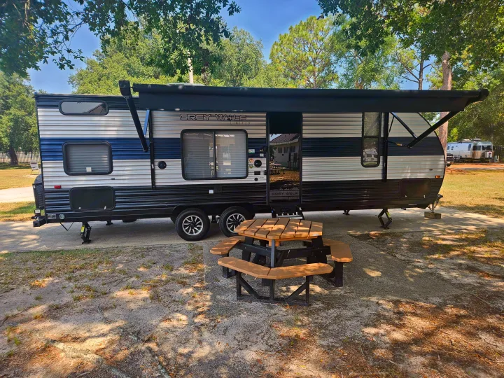 Experience a Grey Wolf travel trailer rv rental at a shady campsite with a picnic table.. Forest River Cherokee Grey Wolf Special Edition 2022