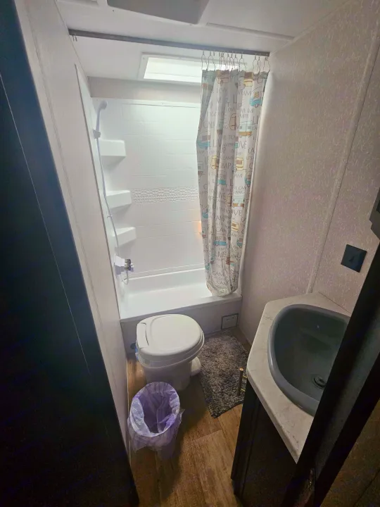Step inside this RV rental bathroom with a compact shower/tub, toilet, and sink, equipped for comfortable travel convenience.. Forest River Cherokee Grey Wolf Special Edition 2022