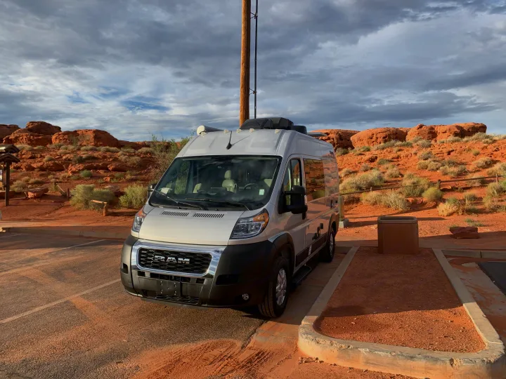 RV rental camper van parked in a scenic desert landscape with red rocks under a cloudy sky.. Thor Motor Coach Scope 2023