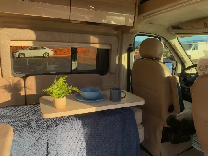 Cozy RV rental interior featuring a table, plant, and seating area with a view of red rocks outside.. Thor Motor Coach Scope 2023