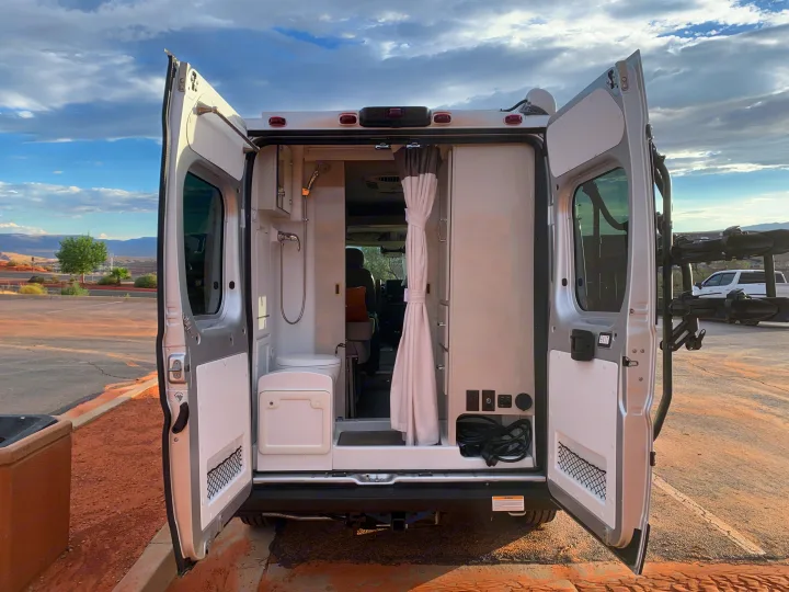 Explore this RV rental's rear with open doors, revealing a functional interior: compact wet bath, power console, and bike rack.. Thor Motor Coach Scope 2023