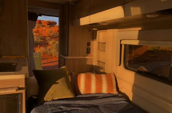 Golden hour in an RV rental: cozy interior with bed, kitchen, and a beautiful desert landscape view.. Thor Motor Coach Scope 2023