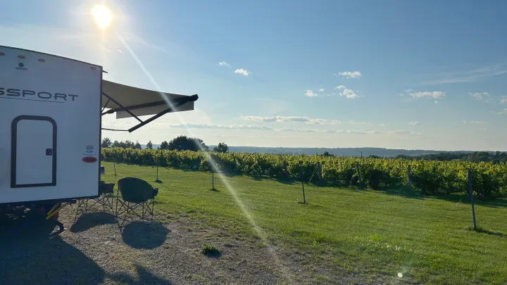Enjoying a scenic RV rental stay at a sunny vineyard. Relax by your RV with stunning views of grapevines and hills.. Keystone RV Passport SL 2022