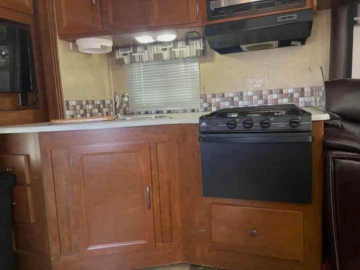 RV rental kitchen: a cozy space with a sink, stove/oven, microwave, and cabinetry for your travels.. Coachmen Pursuit 2014