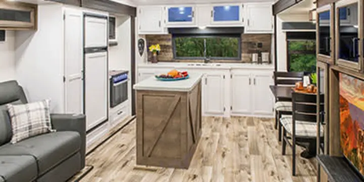 Spacious, modern RV rental interior with light wood floors, featuring a full kitchen, sofa, and dining area.. SportTrek STT333VFK 2023