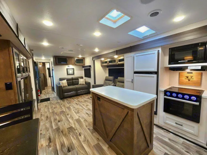 Spacious RV rental interior with a modern kitchen island, comfortable living area, and bright, inviting design.. SportTrek STT333VFK 2023