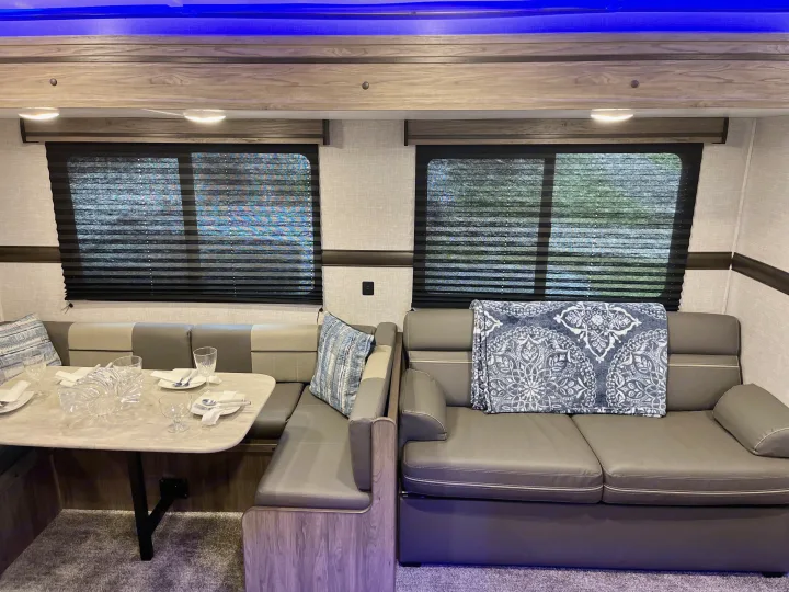 Modern RV rental living space featuring a dining booth, sofa, and ambient blue lighting.. Crossroads RV Zinger Lite 2022