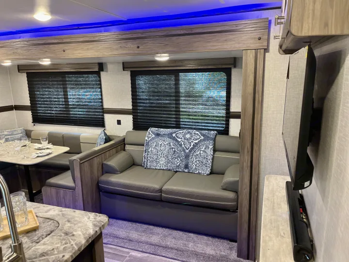 Modern RV rental interior with a comfy sofa, dining area, kitchen, and TV. Ideal for travel comfort.. Crossroads RV Zinger Lite 2022