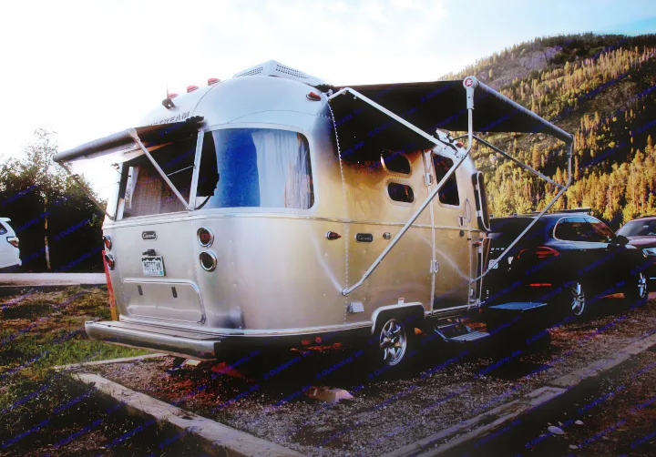 A beautiful Airstream travel trailer (perfect for an rv rental adventure) set up at a mountain campsite under the evening sky.. Airstream Caravel 2022