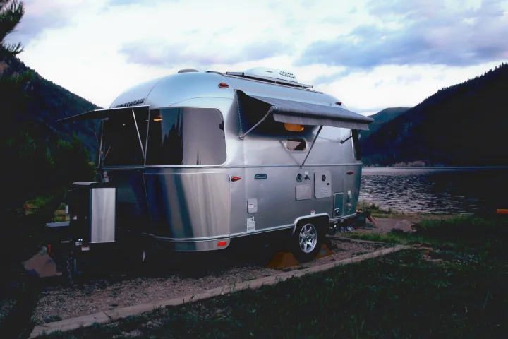 Experience serene lakefront camping with this Airstream rv rental, nestled among mountains and calm waters.. Airstream Caravel 2022