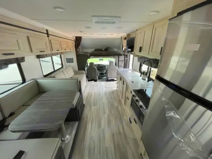 Inside a modern RV rental: a spacious interior with full kitchen (fridge, stove), dinette, sofa, and overhead bunk.. Forest River Sunseeker Classic 2023