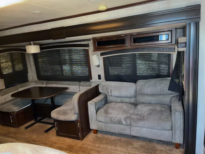 Cozy RV rental interior featuring a gray sofa, dinette, and ample storage for your journey.. Jayco Jay Flight 2018