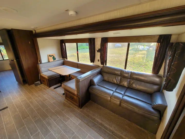 This RV rental offers a spacious living area with a dark gray sofa, light gray dinette, and large windows, showcasing comfort.. Forest River Cherokee 2020