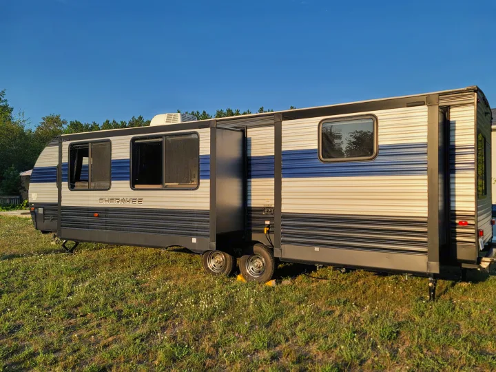 Cherokee travel trailer RV rental parked on grass, ready for adventure under a clear blue sky.. Forest River Cherokee 2020