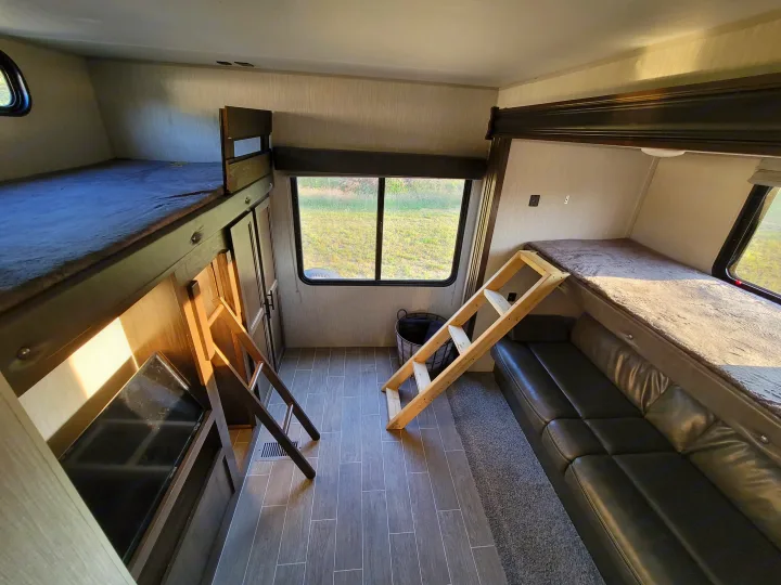 Explore this RV rental's cozy bunkhouse with multiple bunk beds, a sofa, TV, and large windows. Perfect travel interior.. Forest River Cherokee 2020