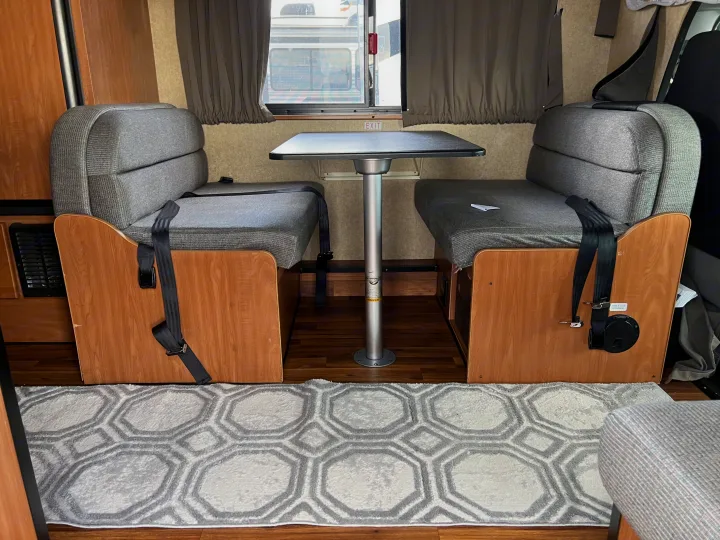 RV rental dinette showing gray benches with seatbelts, a central table, and wood-toned interior details.. Thor Majestic 2017