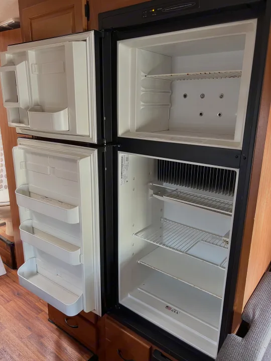 Empty RV refrigerator interior, with wire shelves and door bins, ready for your next rv rental adventure.. Thor Majestic 2017