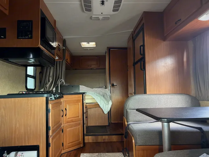 Spacious RV rental interior with kitchen, dinette, and bed area, ideal for comfortable travel and camping adventures.. Thor Majestic 2017
