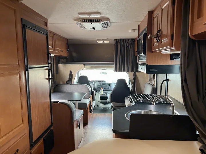 RV rental: Interior showing kitchen with sink/stove, fridge, dinette, overhead bunk, and front cab.. Thor Majestic 2017