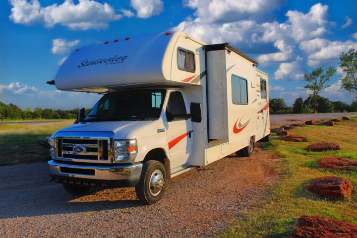 White Sunseeker Class C RV rental parked on a gravel path with a vibrant sky. A spacious motorhome for outdoor travel.. Forest River Sunseeker 2015