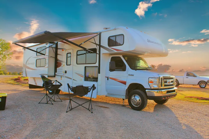 This Sunseeker RV rental is perfectly set up for an outdoor adventure, complete with an awning and chairs at a gravel campsite.. Forest River Sunseeker 2015