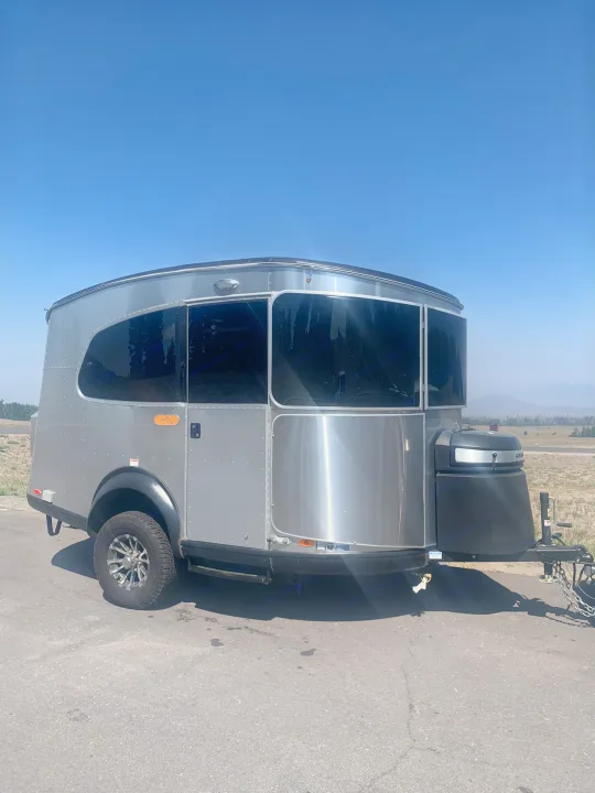 Sleek silver travel trailer, great for an rv rental, parked on asphalt under clear blue skies, ready for outdoor adventures.. Airstream Basecamp 2022