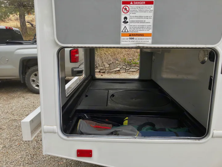 RV rental's spacious pass-through storage bay, loaded with gear, shows important safety warnings.. Majestic Ford 2018
