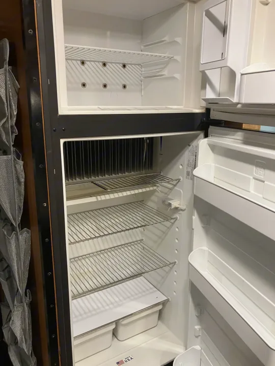 Empty, clean refrigerator in an RV rental, featuring wire shelves, top freezer, and door bins. Ready for your camping adventure.. Majestic Ford 2018
