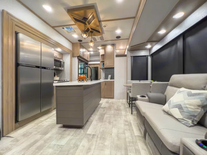 Modern RV rental interior: well-appointed kitchen with island, large fridge, and comfortable living area with sofa and dining.. Grand Design Momentum 2023