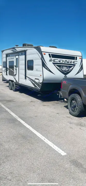 This large gray and black Iconic travel trailer is hitched to a dark pickup truck, perfect for an rv rental adventure.. Eclipse Recreational Vehicles Iconic 2018