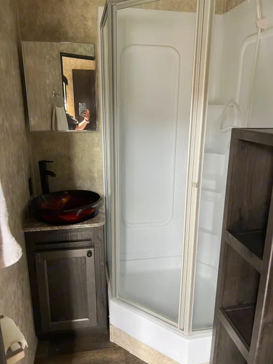 Compact RV rental bathroom featuring a dark wood vanity, red vessel sink, and a corner shower.. Eclipse Recreational Vehicles Iconic 2018