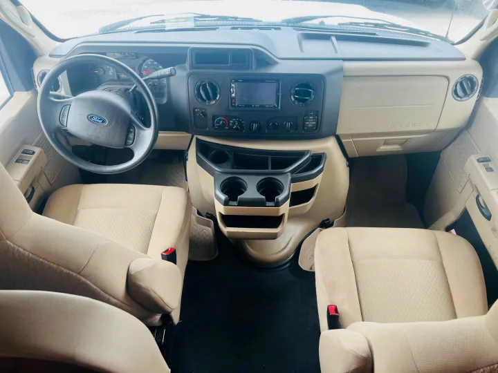 RV rental: Spacious, clean front cabin with Ford dashboard, infotainment system, steering wheel, and beige driver/passenger seats.. Thor Freedom Elite 2020