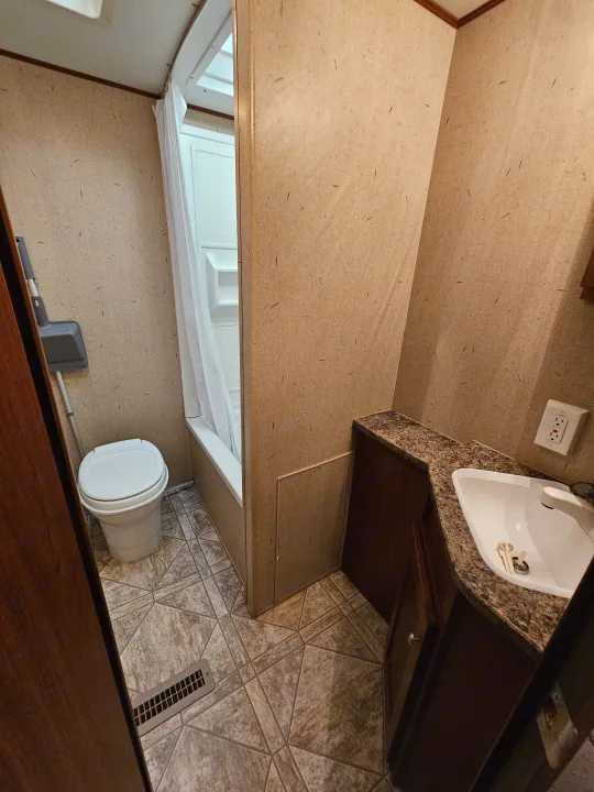 This RV rental bathroom features a compact toilet, shower, and sink vanity. A clean, functional space ideal for travelers.. Crossroads RV Zinger 2010