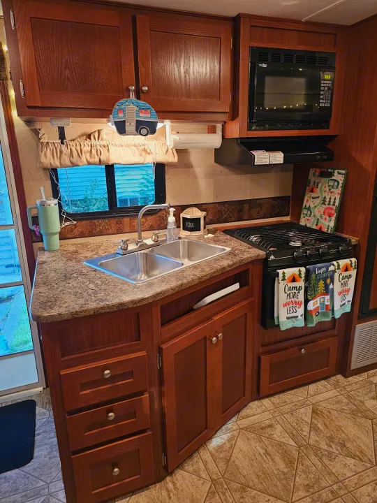 This RV rental's well-equipped kitchen boasts a sink, stove, microwave, wood cabinets, and fun camper-themed accessories.. Crossroads RV Zinger 2010