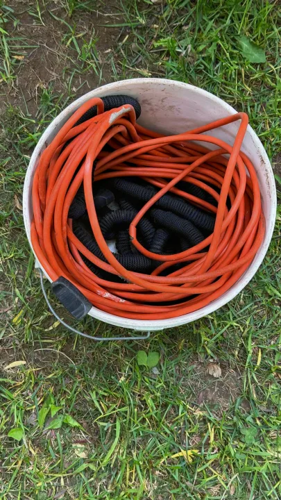 White bucket holding an orange extension cord and black hose – essential utility gear for your RV rental trip.. Coachmen Clipper 2008