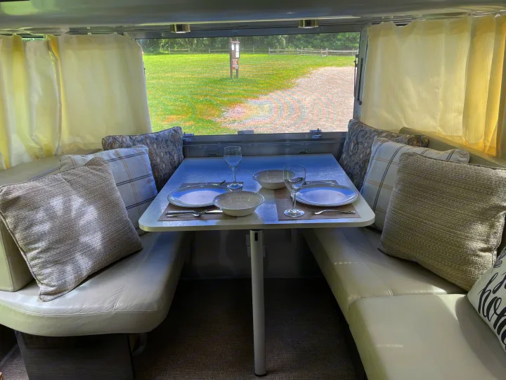 Cozy RV rental dining area with outdoor views. Table set for two in a comfortable camper interior.. Airstream International 2014