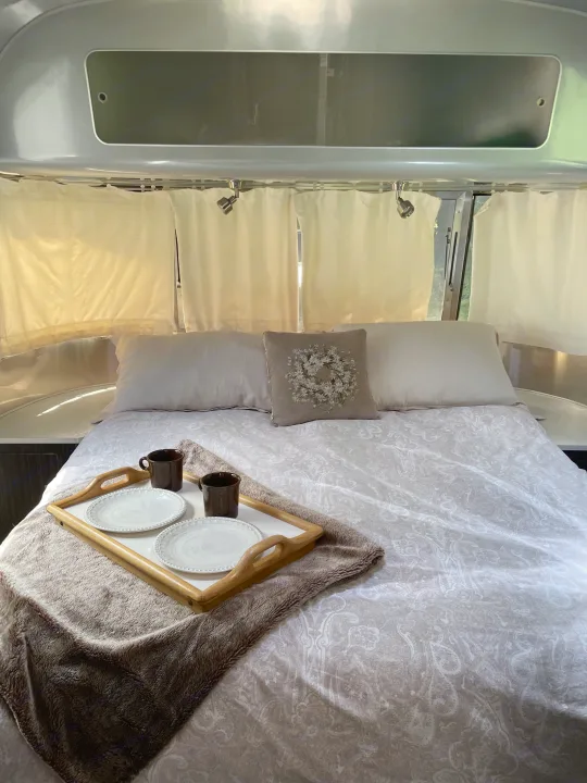 Cozy Airstream RV rental bedroom: A comfortable bed with breakfast tray, pillows, and ambient lighting.. Airstream International 2014
