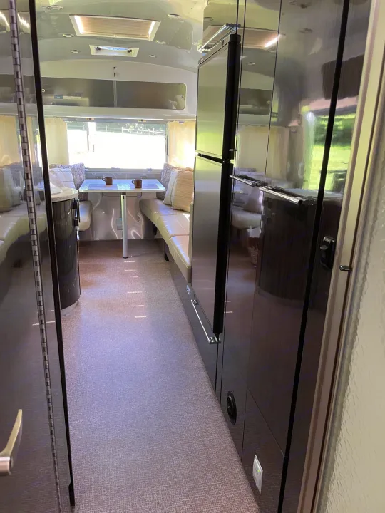 Airstream rv rental interior: view down central aisle with dining booth, kitchen, and living areas.. Airstream International 2014