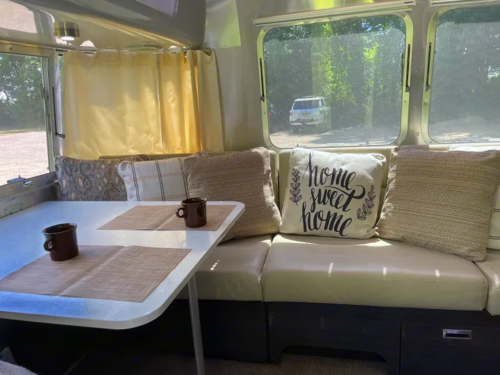 Experience comfort in this RV rental! A well-lit travel trailer dinette with cozy cushions and a 'home sweet home' pillow.. Airstream International 2014