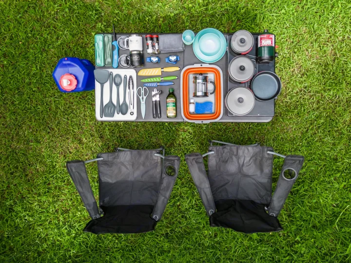 RV rental camping kitchen: Portable cooking gear, two chairs, & essentials laid out on grass for outdoor adventures.. Custom Toyota 4Runner TRD Off-Road 2023