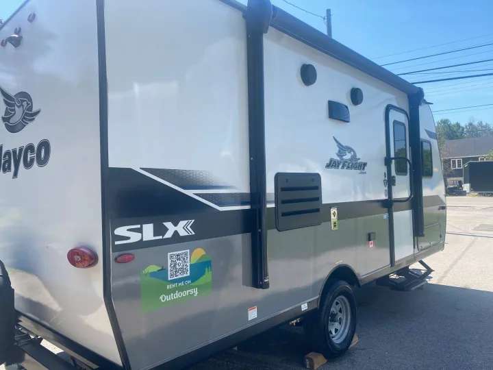 A white and gray Jayco SLX travel trailer, available for **RV rental** via Outdoorsy, parked on asphalt.. Jayco Jay Flight SLX 2022