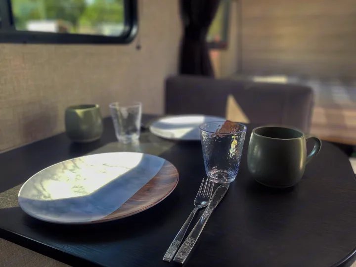 The cozy dining area inside an RV rental, set with two plates, glasses, and cutlery, ready for a meal on your journey.. Jayco Jay Flight SLX 2022
