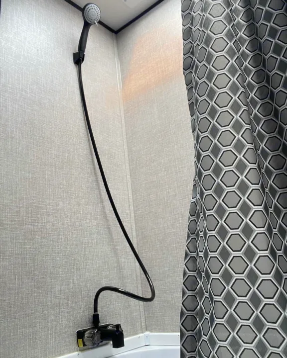 View inside an RV rental's shower stall, featuring a handheld shower head and a gray hexagonal shower curtain.. Jayco Jay Flight SLX 2022