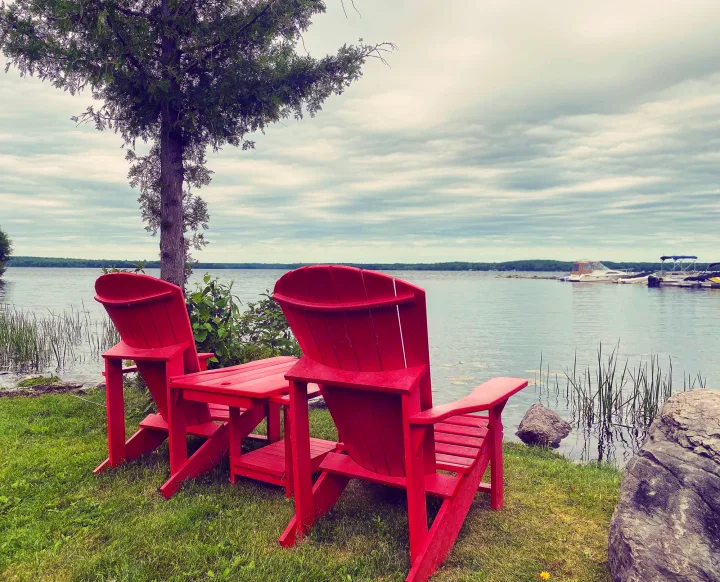 Red Adirondack chairs overlook a peaceful lake. A perfect stop for your RV rental trip!. Jayco Jay Flight SLX 2022
