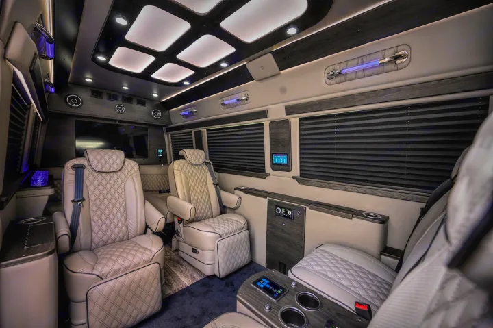 Experience luxury with this RV rental van's interior: plush, diamond-stitched seats, mood lighting, and advanced tech for comfort.. Midwest Automotive Designs Ultimate Coach 2023