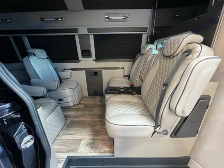 Spacious luxury RV rental interior with plush, light-colored quilted captain's chairs for comfortable travel.. Midwest Automotive Designs Ultimate Coach 2023