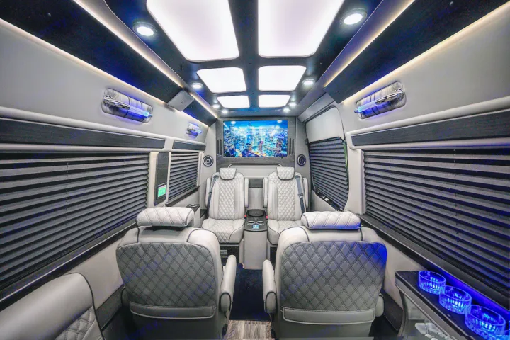 Luxury custom van interior, ideal for RV rental. Features quilted seating, large TV, and elegant ambient lighting.. Midwest Automotive Designs Ultimate Coach 2023