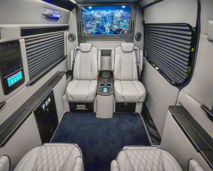 Luxury RV rental interior: plush diamond-stitched captain's chairs, a large screen, and integrated control panels.. Midwest Automotive Designs Ultimate Coach 2023