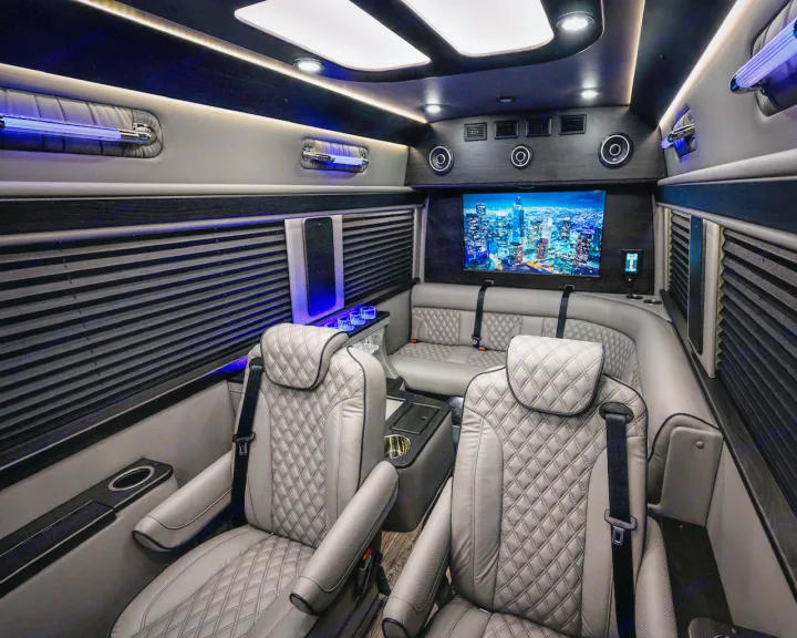 Luxury RV rental interior: spacious custom van with quilted seats, ambient lighting, & large TV display.. Midwest Automotive Designs Ultimate Coach 2023